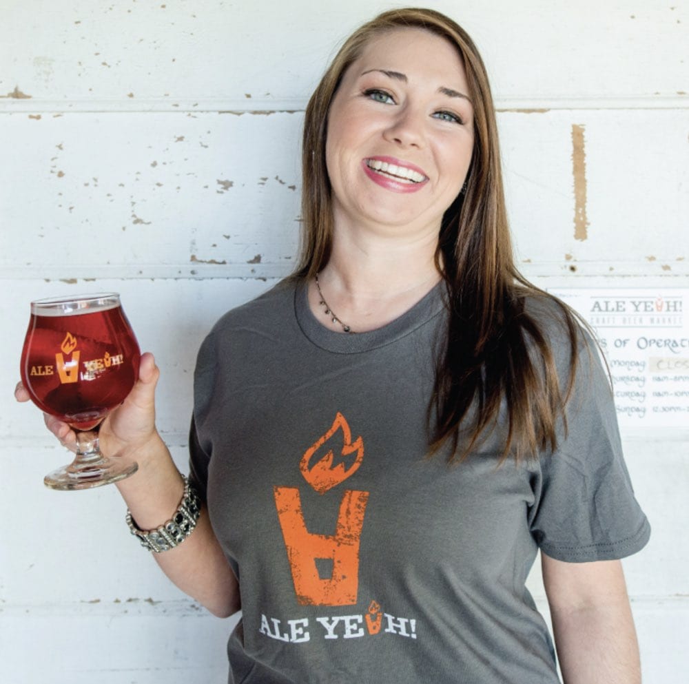 Woman holding a glass of beer at Atlanta restaurant event, smiling.